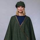 Woman wearing a green cape and matching hat against a gray background