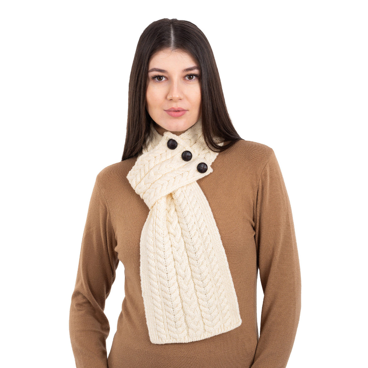 Woman wearing a beige sweater and cream scarf with black buttons on a white background