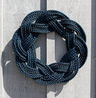 Navy blue rope knot wreath on a light wooden background