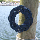 Navy blue rope tied in a knot on a wooden post with a marina in the background