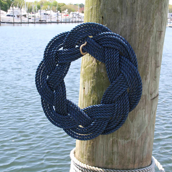 Navy blue rope tied in a knot on a wooden post with a marina in the background