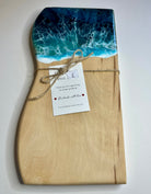Wooden cutting board with ocean design and a tag on a white background