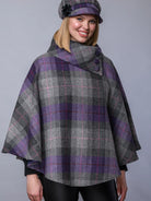 Woman wearing a plaid cape and matching hat against a gray background
