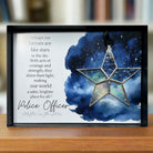 Framed artwork with star design and text about police officers on a wooden surface.