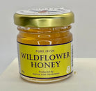 Jar of pure Irish wildflower honey with a gold lid on a white background
