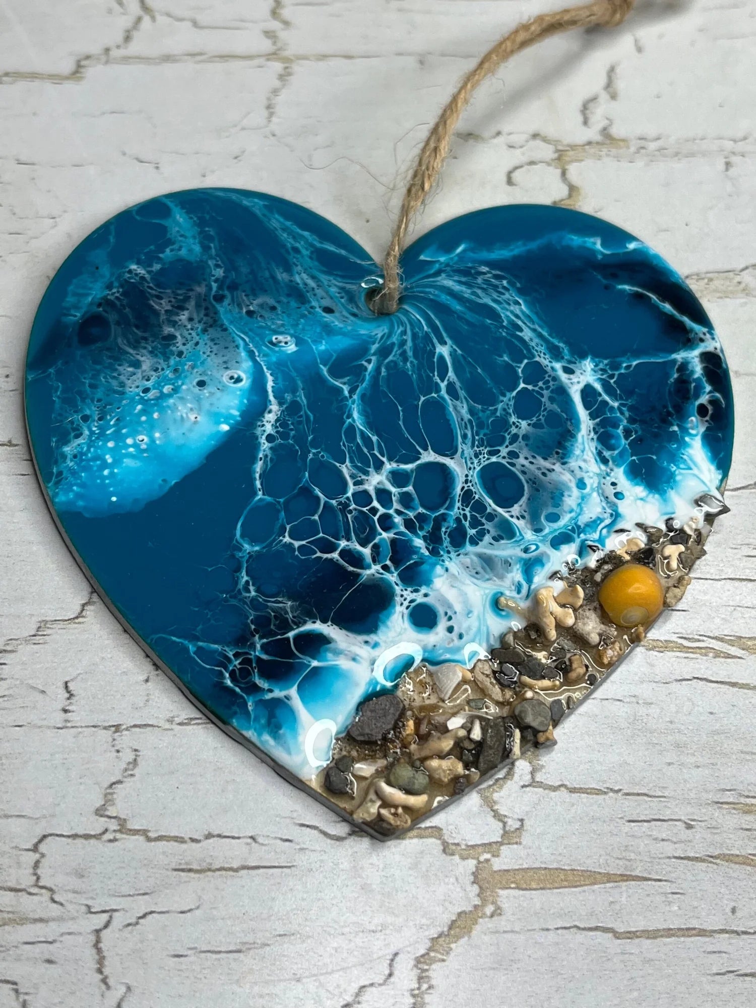 Heart-shaped blue ceramic ornament with beach elements on a textured surface