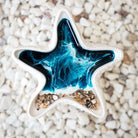 Star-shaped trinket dish with blue and white design on a pebbly surface