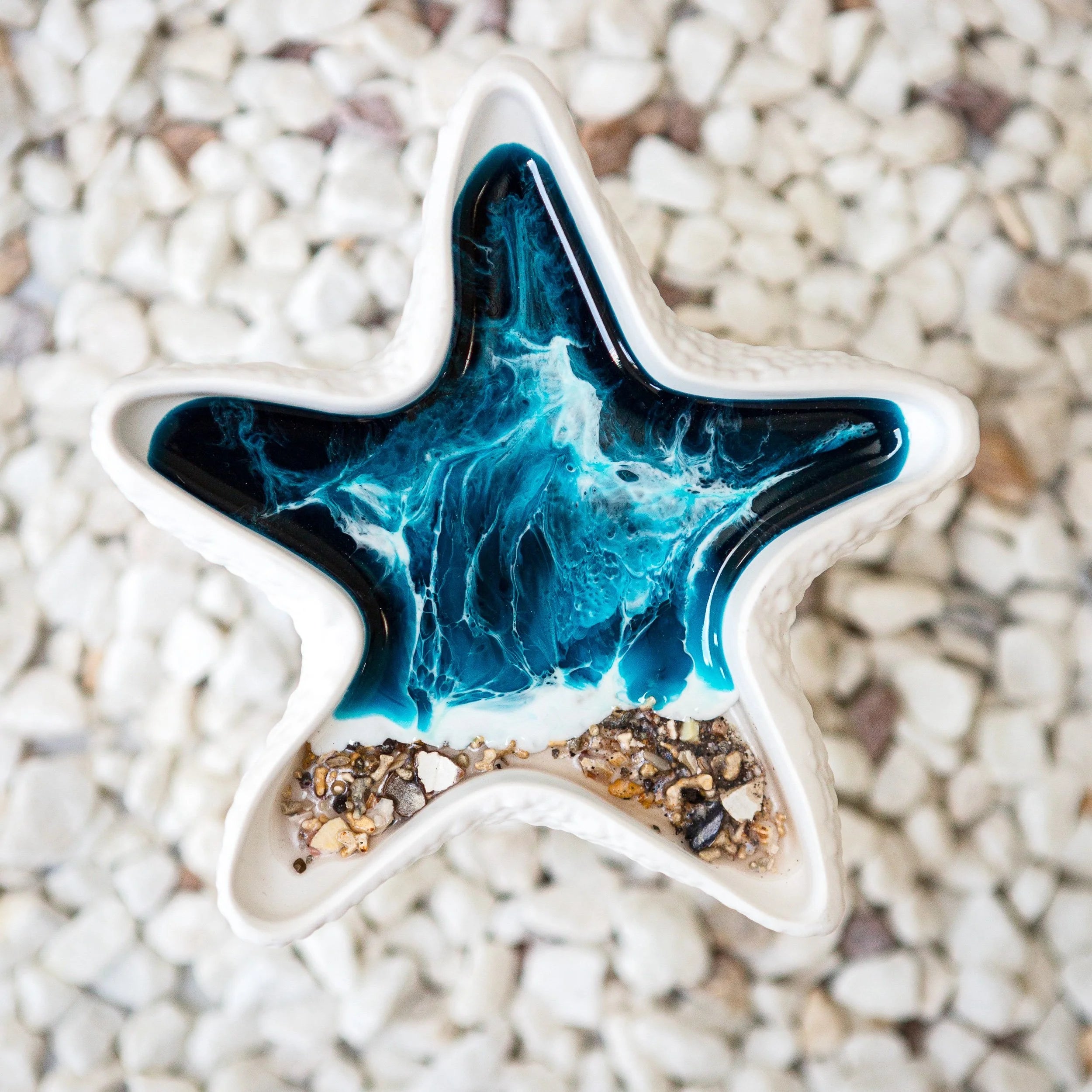 Star-shaped trinket dish with blue and white design on a pebbly surface