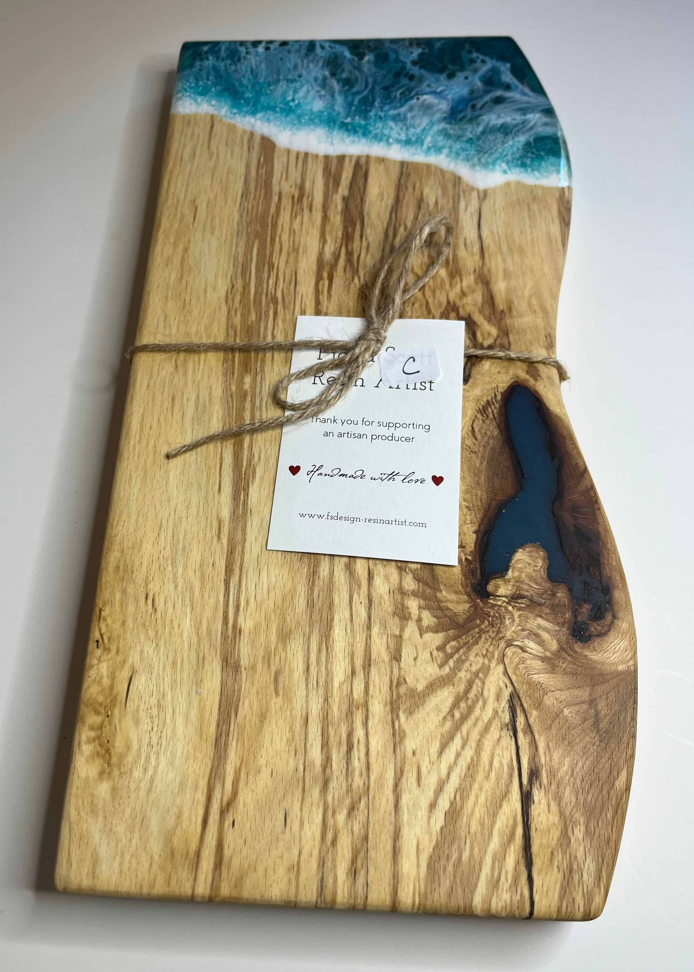 Wooden cutting board with ocean design and a tag on a white background