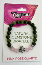 Green gemstone bracelet with pink rose quartz and a shamrock charm on Connemara packaging.