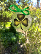 Decorative shamrock ornament with a green ribbon against a natural background