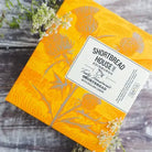 Shortbread packaging with floral design and 'Shortbread House of Edinburgh' label on a wooden surface.