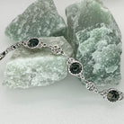 Silver bracelet with green gemstones on a background of green stones
