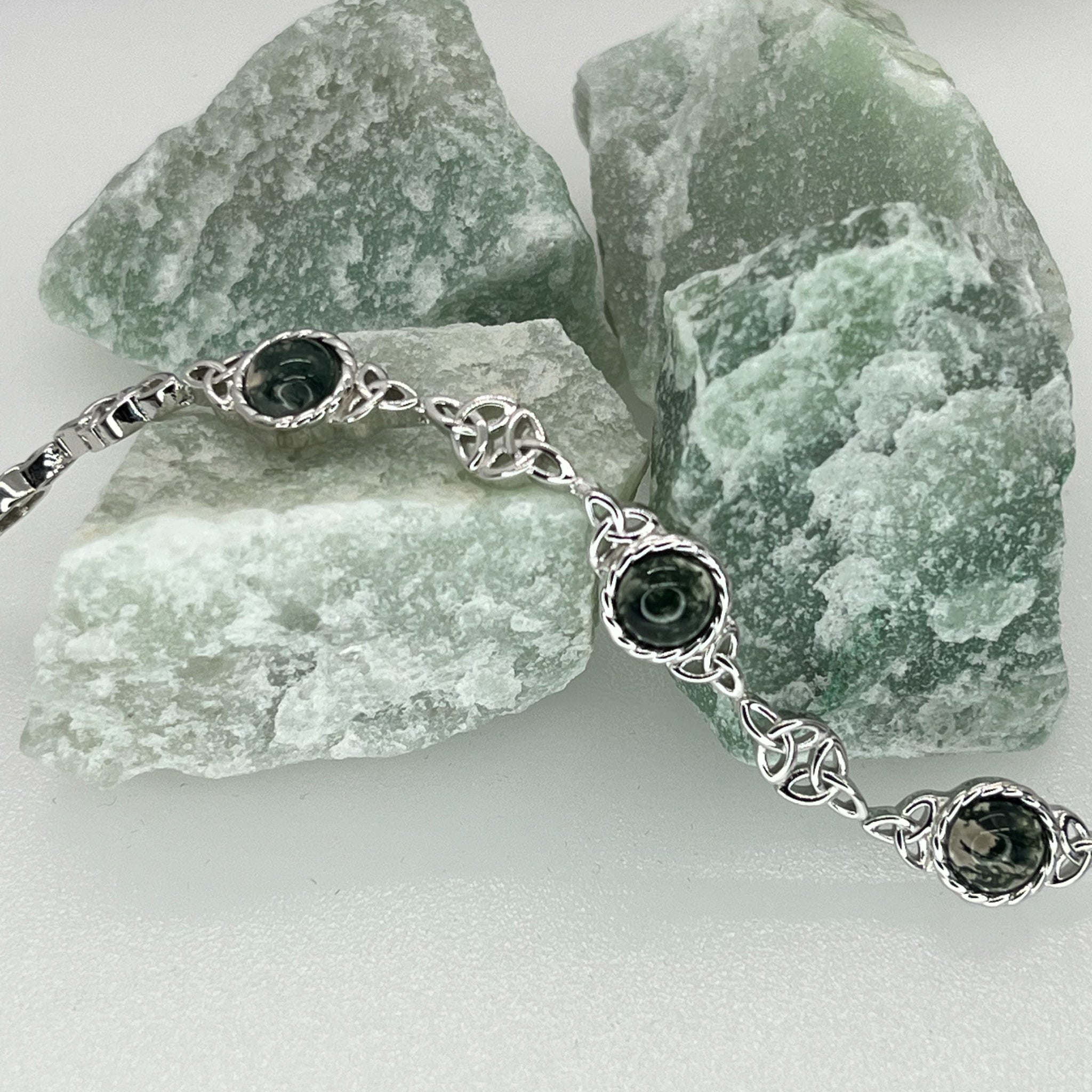 Silver bracelet with green gemstones on a background of green stones