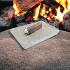 Wooden fire starter on a stone surface with flames in the background