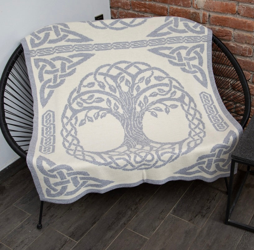 Blanket with tree design and Celtic knot patterns draped over a chair.