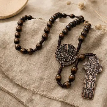 A dark brown wooden bead rosary with a round medallion and a cross pendant, displayed on a textured beige linen fabric.
