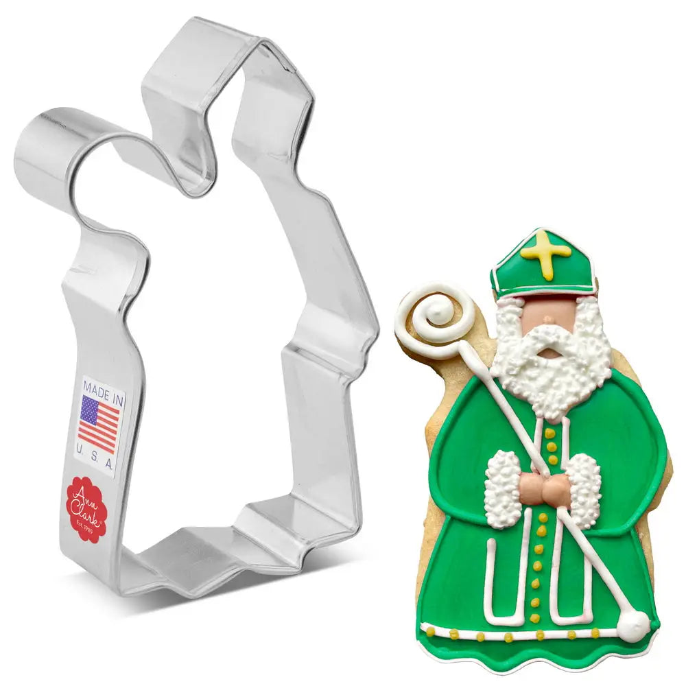 Cookie cutter shaped like a bishop figure with a cookie decorated in the same style on a white background.