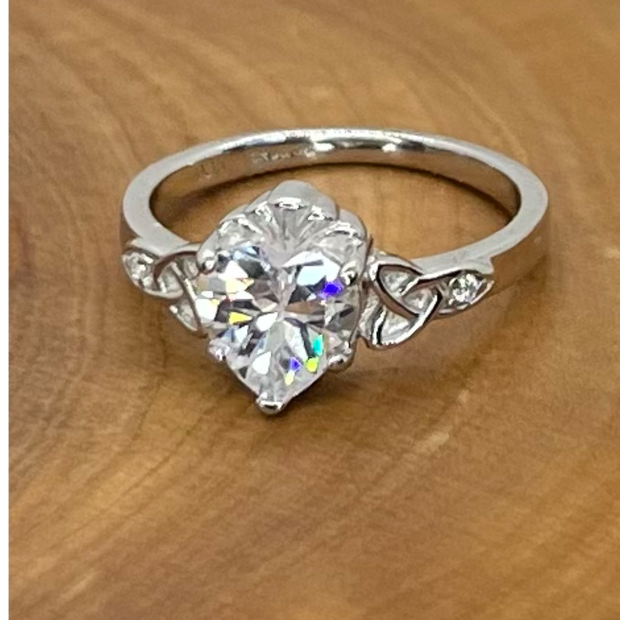 Silver ring with a large diamond on a wooden surface