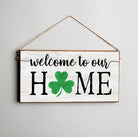 Wooden sign with 'welcome to our HOME' text and a green clover on a gray background