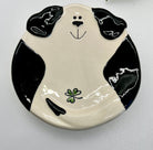 Ceramic plate shaped like a black and white dog face with a clover on a white background