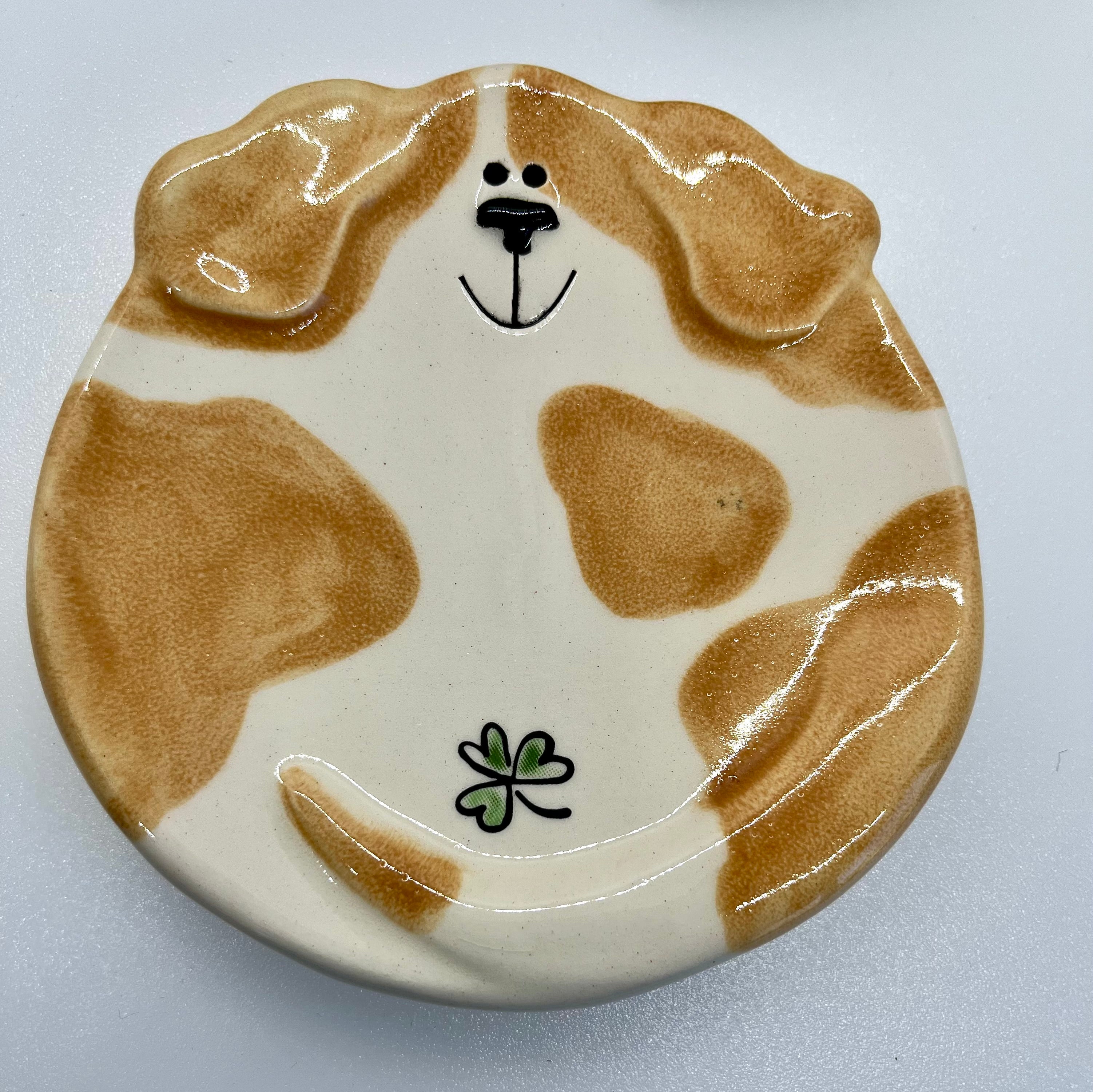 Ceramic plate shaped like a dog with a four-leaf clover on a white background