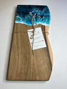 Wooden cutting board with ocean design and tag on a white background