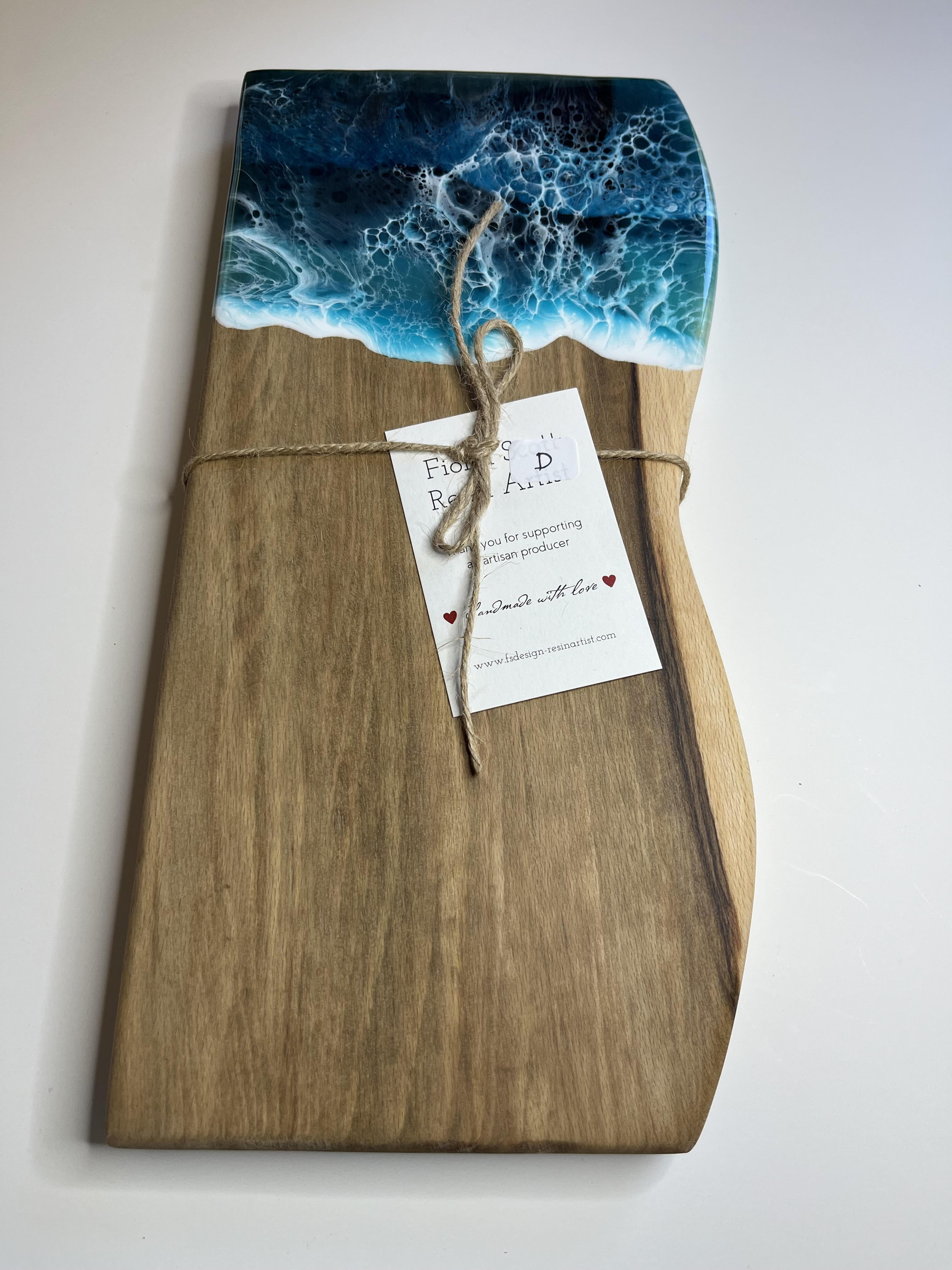 Wooden cutting board with ocean design and tag on a white background
