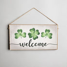 Decorative sign with green shamrocks and 'welcome' text on a light background